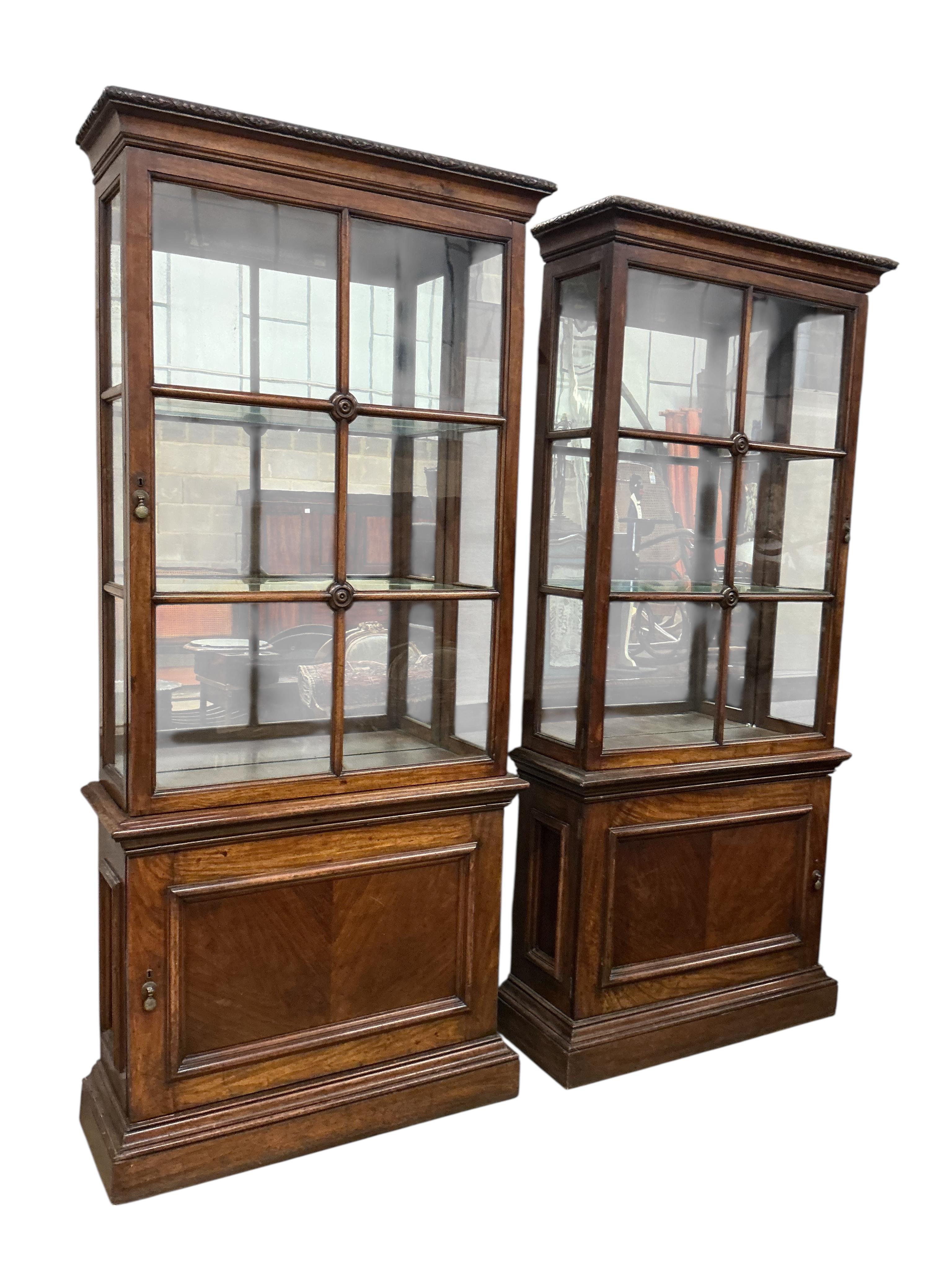 A pair of 1930's walnut vitrines, with single bar glazed doors over single panelled doors, on plinth feet, width 94cm, depth 35cm, height 212cm
